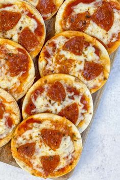 small pepperoni pizzas sitting on top of a cutting board