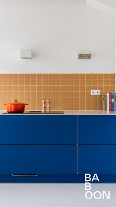 a kitchen with blue cabinets and tile backsplashing on the wall above it