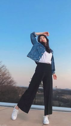 a woman in white shirt and black pants posing for the camera with her hands behind her head