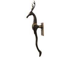 a black and gold horse hook on a white wall in the shape of a giraffe