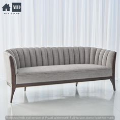 a gray couch sitting on top of a white floor next to a curtained wall