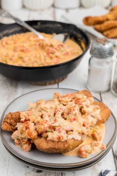 a plate with some food on it next to a skillet filled with cheese sauce