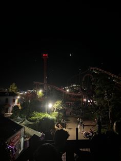 an amusement park lit up at night with people on the ground and in the dark