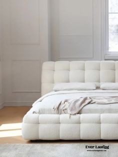 a white couch sitting in front of a window next to a rug on the floor