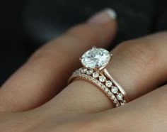 a woman's hand with a diamond ring on top of her finger and the other hand holding an engagement ring