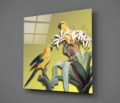 two yellow birds perched on top of a tree branch next to some white and green flowers