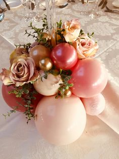 some balloons and flowers on a table with silver place settings in the centerpieces