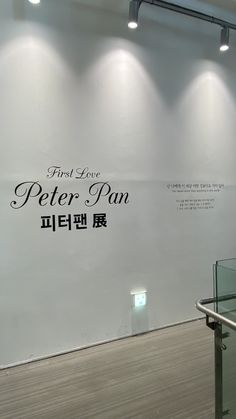 an empty room with white walls and wood flooring in front of the wall is a sign that says peter pan