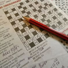 a red pencil sitting on top of a crossword puzzle