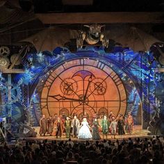 a group of people standing on top of a stage in front of a giant clock