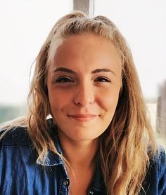 a woman with long blonde hair wearing a denim shirt and looking at the camera smiling