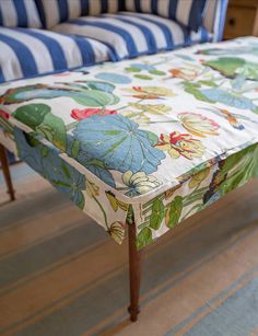 an upholstered bench with blue and white striped cushions on it's sides