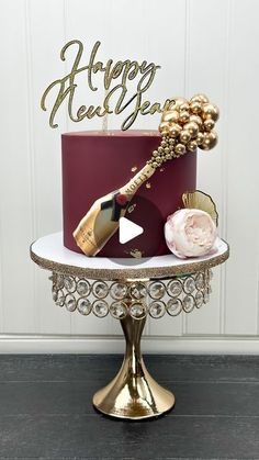 a red and gold happy new year cake sitting on top of a white table next to a wine bottle