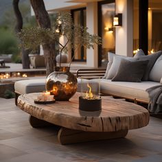 a wooden table with candles on it in front of a couch and patio area at night