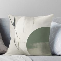 a white and green throw pillow sitting on top of a gray couch next to pillows