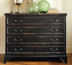 a black dresser with green glass vases on top