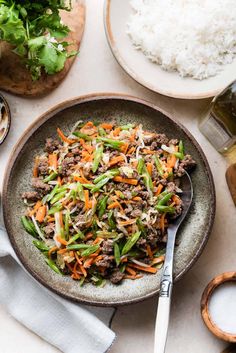 a bowl filled with meat and veggies on top of a table next to other foods