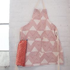 an apron hanging on the wall next to a red and white polka dot pot holder