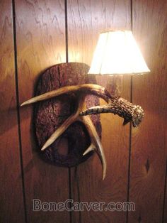 a deer's head mounted to the side of a wooden wall next to a lamp