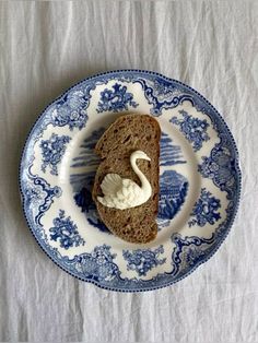 a piece of bread with cream on it sitting on top of a blue and white plate