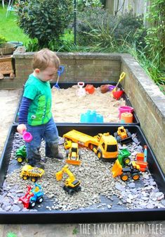 a young boy playing with toys in a sand and water play area at his backyard