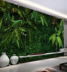 a living room with green plants on the wall and white vases sitting in front of it