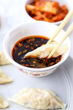 dumplings with sauce and chopsticks in a bowl on a white tablecloth