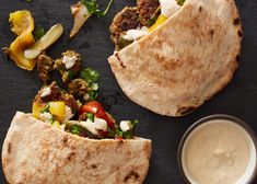 two pita breads on a black surface next to a bowl of ranch dressing