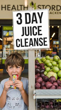 a young boy eating a piece of fruit next to a sign that says 3 day juice cleanse