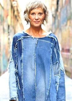 an older woman is walking down the street with her hand in her pocket and wearing a denim jacket