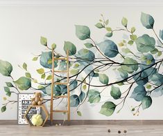 a tree branch with green leaves painted on it's wall next to a ladder