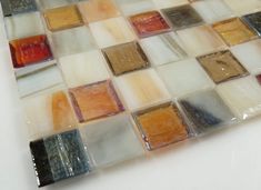 a white table topped with lots of different colored glass tiles