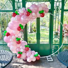 a balloon arch is decorated with pink and green balloons