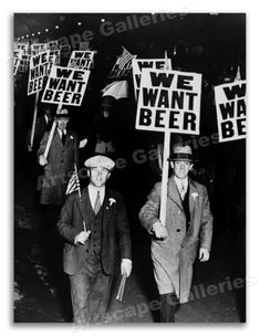 two men walking down the street holding signs that say we want beer and one man with a hat