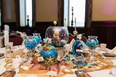 the table is set with silverware and blue glass vases on top of it