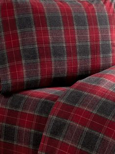 a red and black plaid comforter on a bed with matching pillowcases in the background