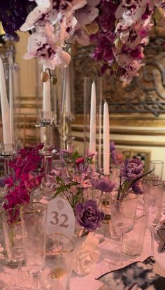 the table is set with candles, flowers and glassware for an elegant dinner party