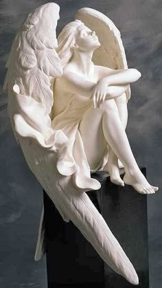 an angel statue sitting on top of a black box