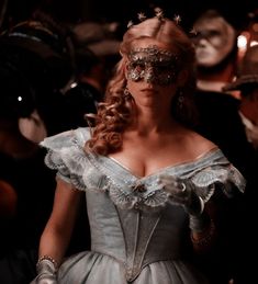 a woman wearing a mask and dress in a crowd