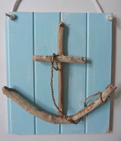 a cross made out of driftwood is hanging on a blue wooden paneled wall