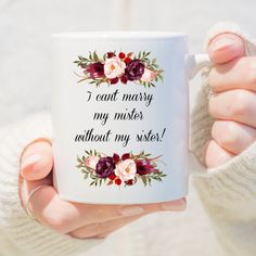 a woman holding a coffee mug with flowers on it that says i can't marry my mister without my sister