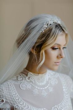 a woman wearing a wedding veil with a tiara on her head and hair comb