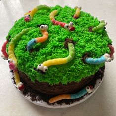 a cake with green frosting and worms on it