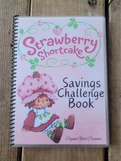 the strawberry shortcake savings challenge book is sitting on top of a wooden table with it's cover open