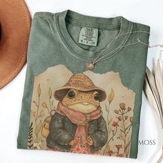 Title: "Retro Cottagecore Toad Comfort Color Shirt | Vintage-inspired Nature Tee with Care Instructions and Sizing Tips" Description: Step into a whimsical world of nostalgia with our Retro Cottagecore Toad Comfort Color Shirt. Inspired by the enchanting allure of cottagecore aesthetics and vintage charm, this tee features a delightful depiction of a toad in a retro style, capturing the essence of nature's beauty and simplicity. Crafted on Comfort Color 1717, our shirt offers unparalleled comfor Cottagecore Workout Clothes, Cool T-shirts, Nature Inspired Clothes, Cute Shirts Aesthetic, Cottagecore T Shirt, Retro Cottagecore, Cottagecore Shirt, Nature Tees, Frog And Toad