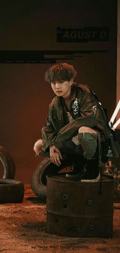 a young man sitting on top of an old tire