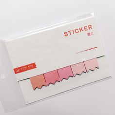 a package of stickers with pink and red paper on it's side, in front of a white background