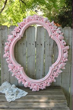 a pink frame sitting on top of a wooden table next to a white doily