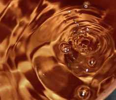 a close up view of water in a bowl with orange light reflecting on the surface