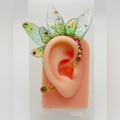 a pink ear with green and yellow wings on it